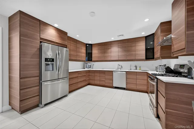 a large kitchen with stainless steel appliances kitchen island granite countertop a sink refrigerator and cabinets