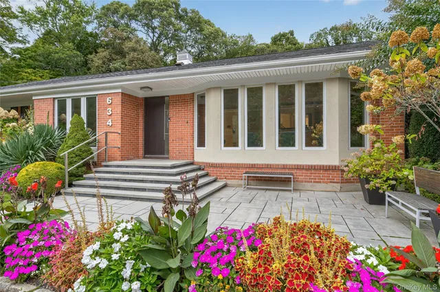a front view of house and yard with beautiful flowers