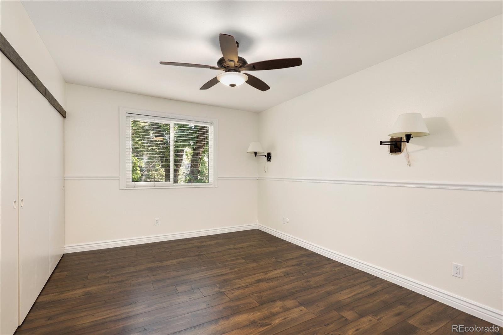 8335 Fairmount Drive, Unit 1202 Denver, CO 80247 - Photo 14 of 28 an empty room with wooden floor fan and windows
