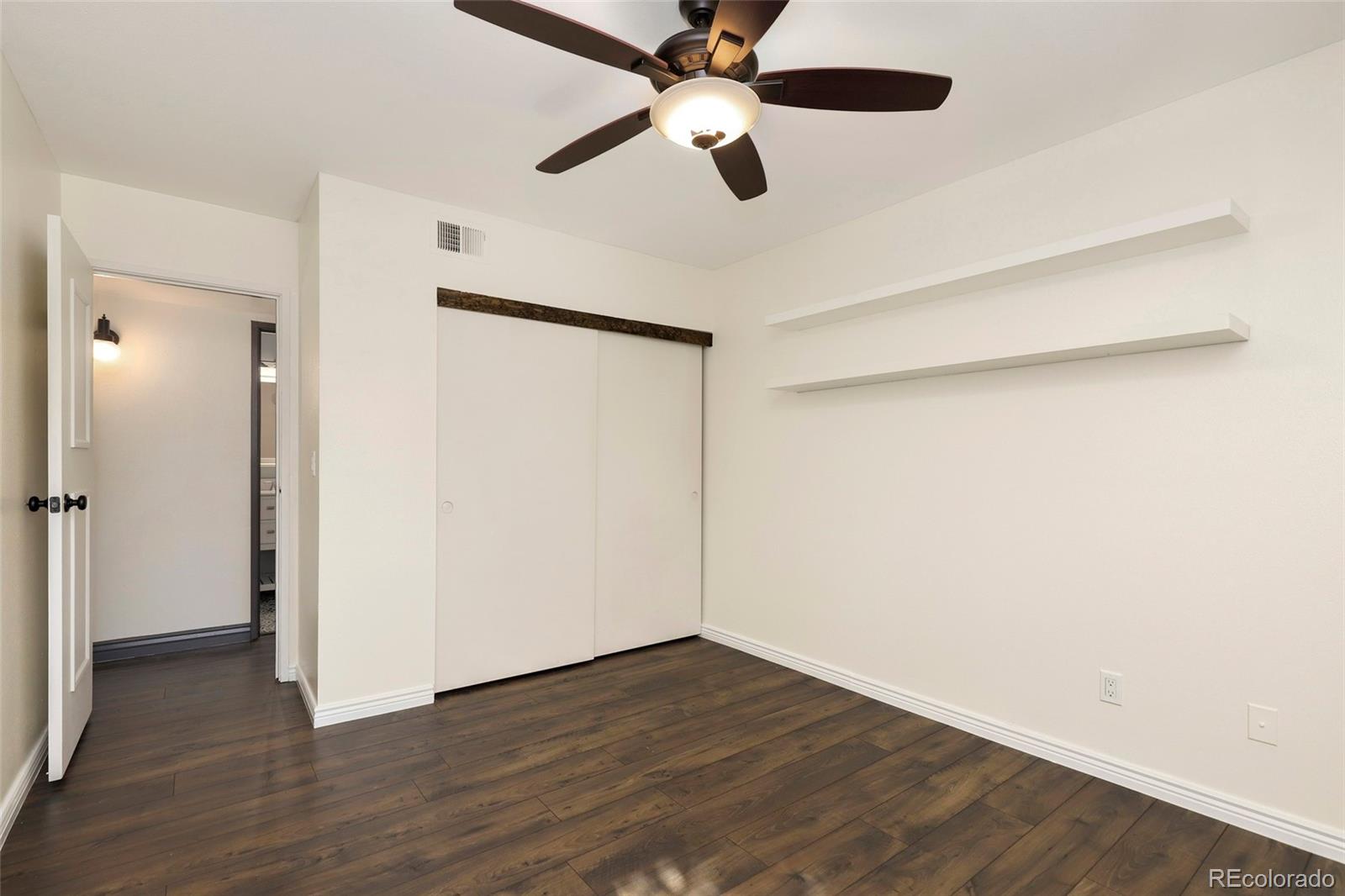 8335 Fairmount Drive, Unit 1202 Denver, CO 80247 - Photo 18 of 28 an empty room with wooden floor a ceiling fan and closet