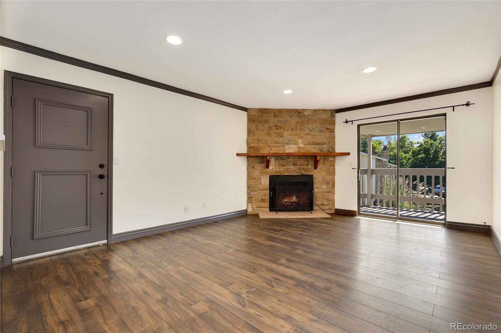 8335 Fairmount Drive, Unit 1202 Denver, CO 80247 - Photo 5 of 28 an empty room with wooden floor fireplace and windows