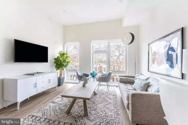 a living room with furniture a flat screen tv and a floor to ceiling window