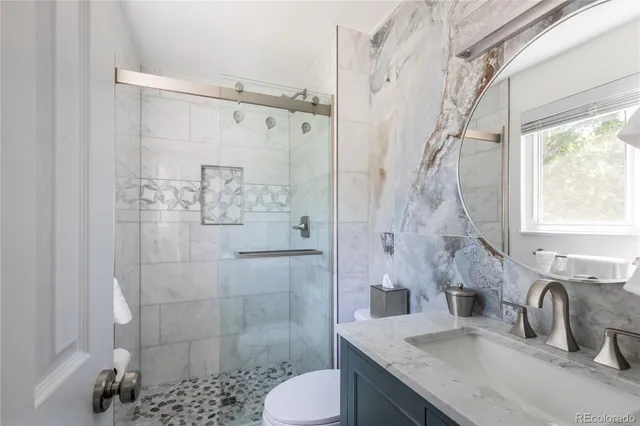 a bathroom with a granite countertop sink toilet and shower