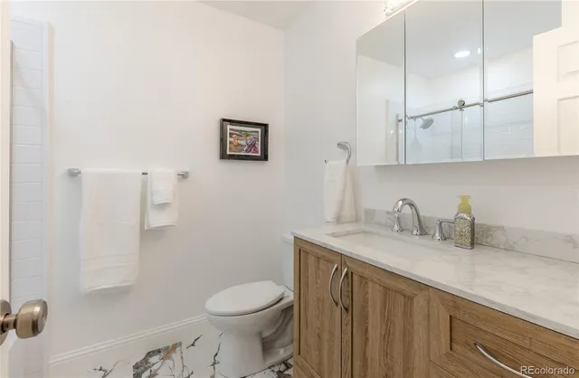 a bathroom with a granite countertop sink a toilet and a mirror