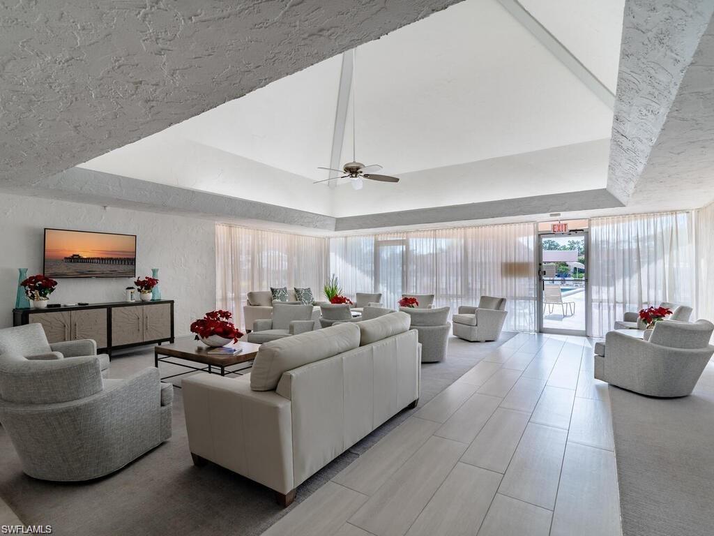 170 Turtle Lake Court, Unit 103 Naples, FL 34105 - Photo 31 of 37 Living area with a tray ceiling, plenty of natural light, a ceiling fan, and a textured wall