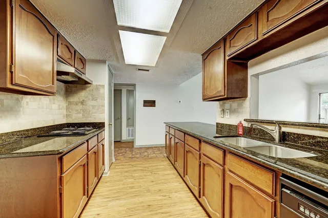 a kitchen with granite countertop stainless steel appliances a sink dishwasher refrigerator stove and cabinets