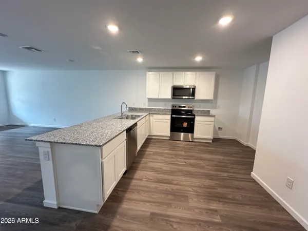 a large kitchen with stainless steel appliances granite countertop a stove and a wooden floors