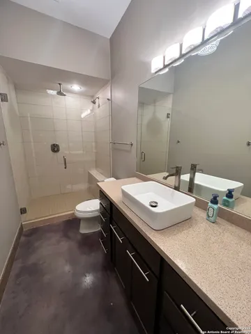 a bathroom with a sink a toilet a mirror and shower