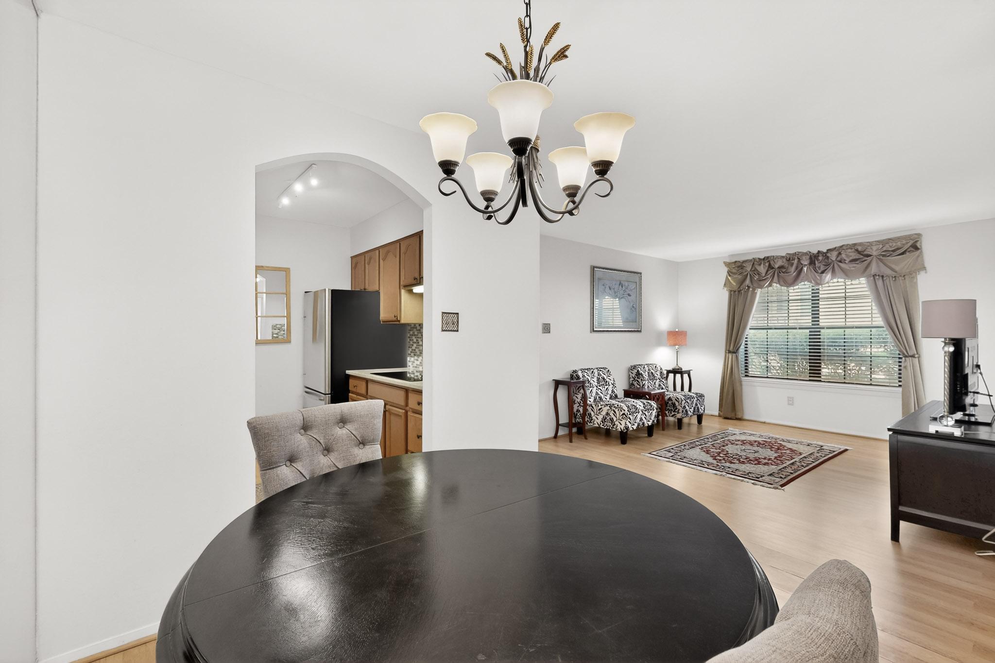 8210 Bent Tree Road, Unit 104 Austin, TX 78759 - Photo 8 of 39 Dining area featuring light wood-type flooring, a chandelier, and arched walkways