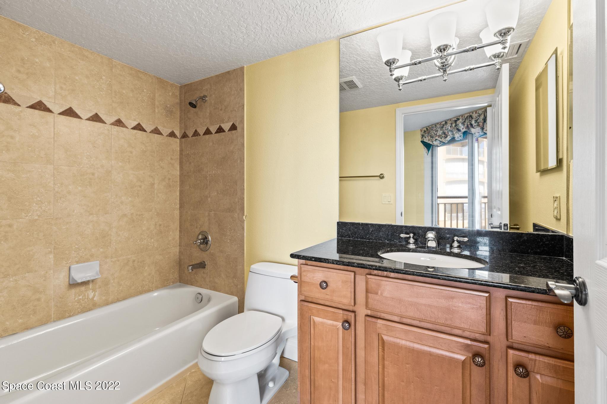 1095 Florida A1A, Unit 2301 Satellite Beach, FL 32937 - Photo 17 of 26 a bathroom with a granite countertop sink toilet and shower