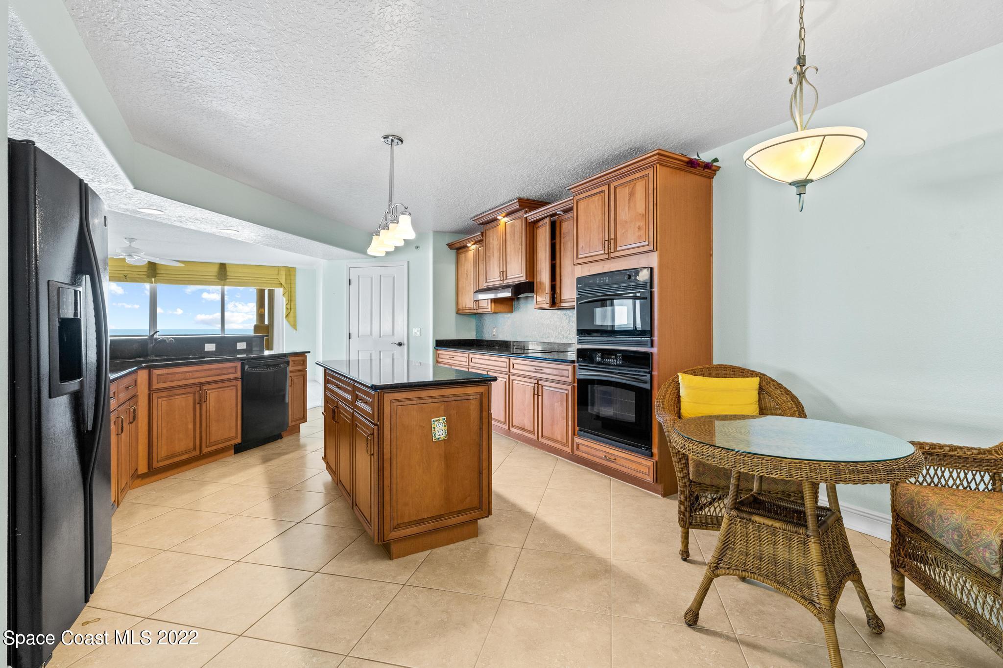 1095 Florida A1A, Unit 2301 Satellite Beach, FL 32937 - Photo 3 of 26 a kitchen with granite countertop a sink cabinets and stainless steel appliances