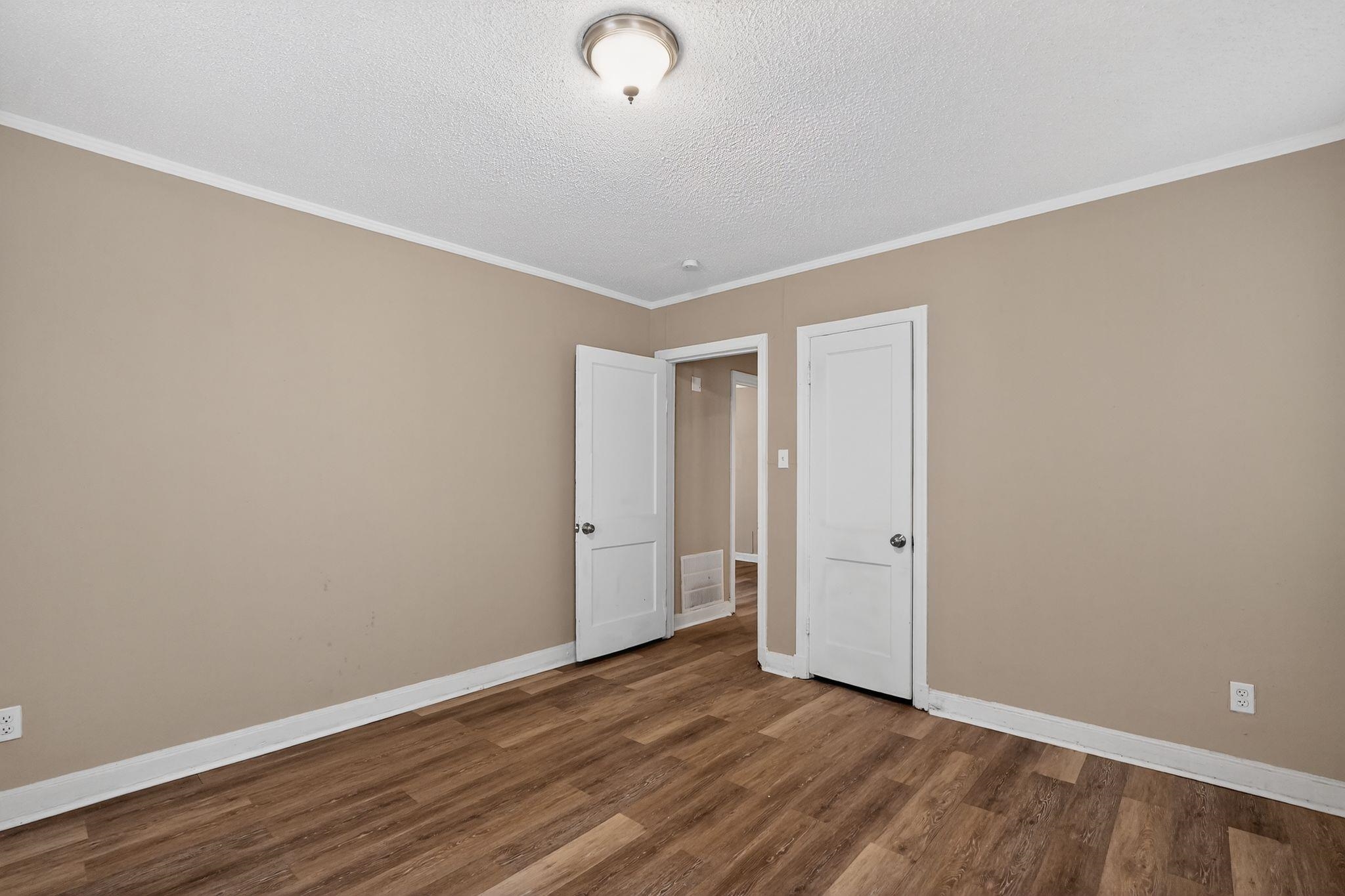 356 Hewlett Road Memphis, TN 38109 - Photo 14 of 30 Unfurnished room featuring crown molding, dark wood-style flooring, and a textured ceiling