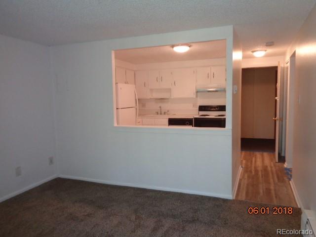 1302 South Parker Road, Unit 216 Denver, CO 80231 - Photo 6 of 13 an empty room with wooden floor and a kitchen