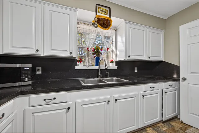 a kitchen with white cabinets and sink