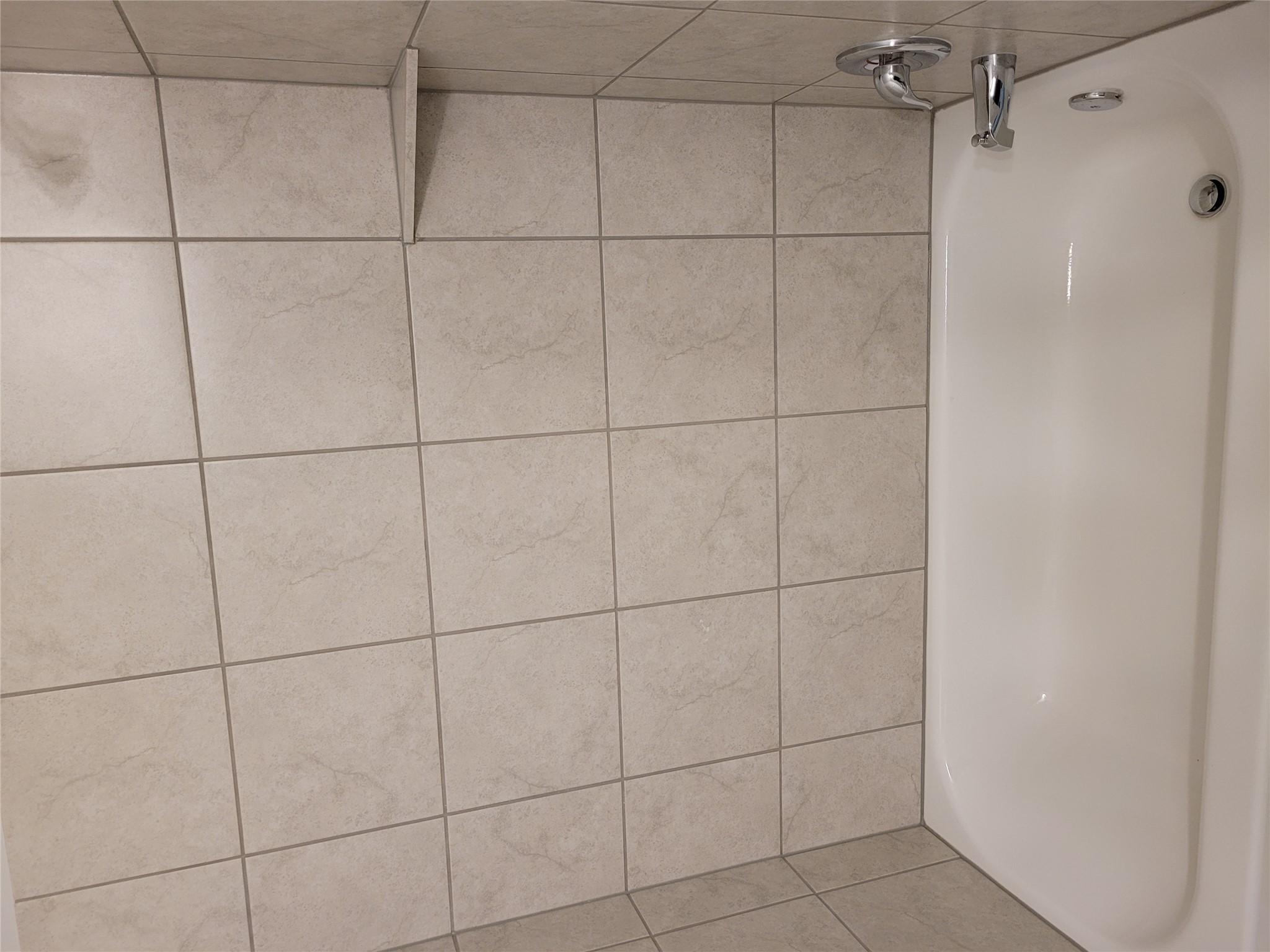 131 Wild Wind Cove Jarrell, TX 76537 - Photo 5 of 26 Bathtub with chrome fixtures, complete with a corner shelf and beige square wall tiles