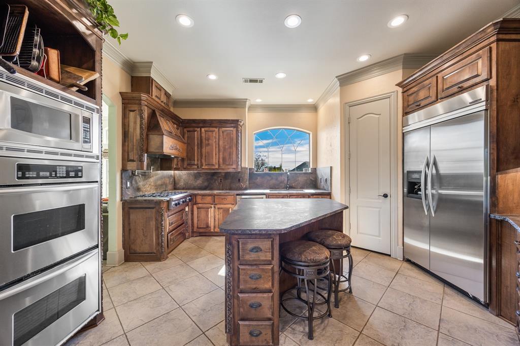 530 Ridge Point Drive Heath, TX 75126 - Photo 10 of 39 Kitchen features a built-in refrigerator, pot filler, double ovens, and exquisite Brazilian granite countertops!