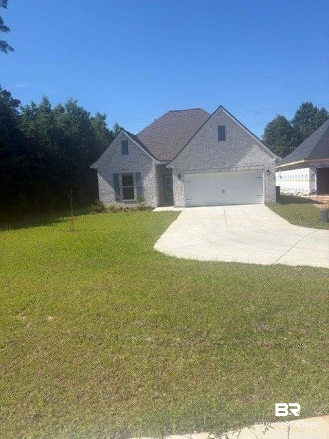 400 Sutton Lane Foley, AL 36535 - Photo 1 of 3 Contemporary residence featuring a light-colored brick exterior, a dark shingle roof, a two-car garage, gray window shutters, and a concrete driveway