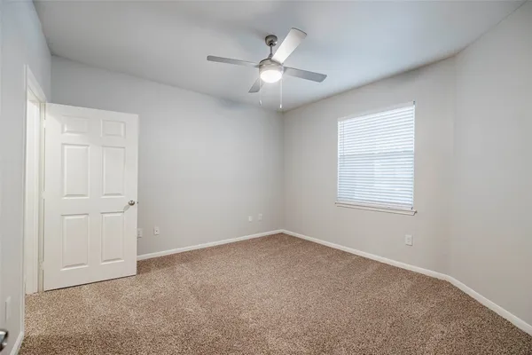 an empty room with a window and a ceiling fan