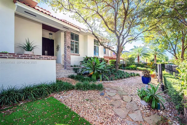 a view of a yard with plants and large trees