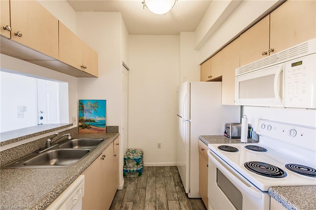 1200 Reserve Way, Unit 302 Naples, FL 34105 - Photo 9 of 12 a kitchen that has a sink and a stove
