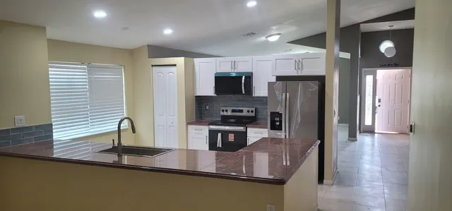 a kitchen with stainless steel appliances granite countertop a refrigerator a sink and a stove