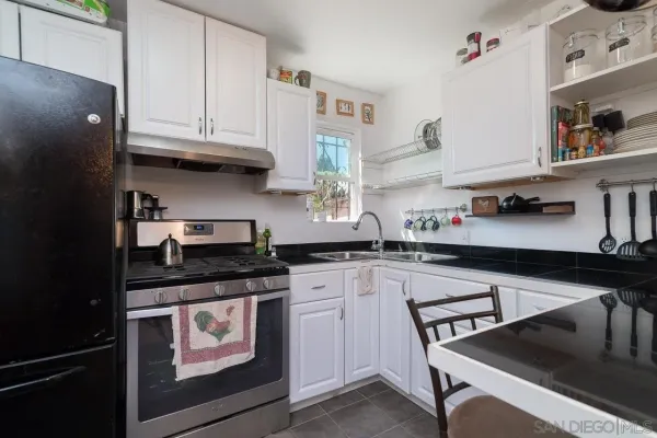 a kitchen with stainless steel appliances granite countertop a sink dishwasher a refrigerator and a stove with wooden floor
