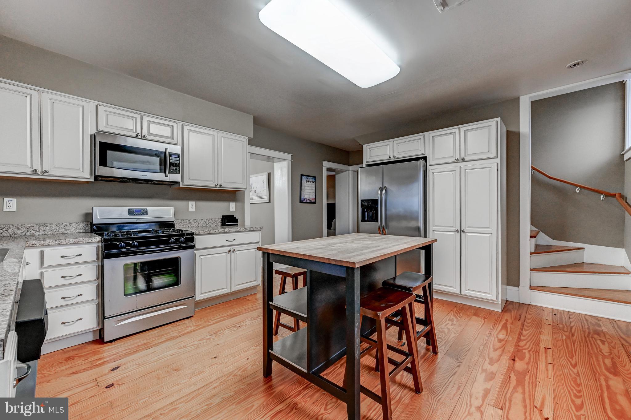 13401 Manor Road Baldwin, MD 21013 - Photo 42 of 46 a kitchen with stainless steel appliances a stove a sink dishwasher a refrigerator with a dining table and chairs with wooden floor