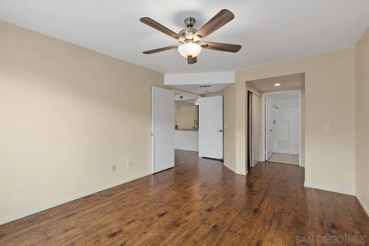 405 Stoney Point Way, Unit 89 Oceanside, CA 92058 - Photo 14 of 32 an empty room with wooden floor and a ceiling fan