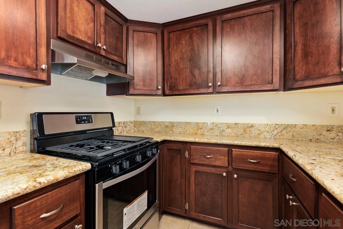 405 Stoney Point Way, Unit 89 Oceanside, CA 92058 - Photo 3 of 32 a kitchen with granite countertop wood cabinets stainless steel appliances and a sink