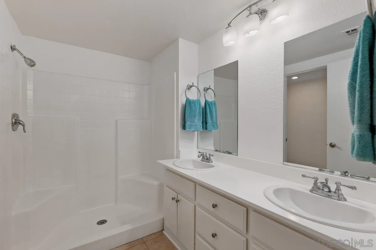 405 Stoney Point Way, Unit 89 Oceanside, CA 92058 - Photo 8 of 32 a bathroom with a shower sink vanity and mirror