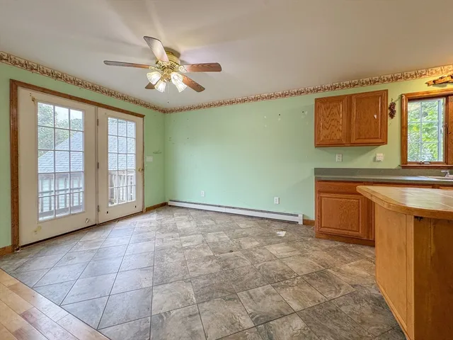 a view of an empty room with window and kitchen view