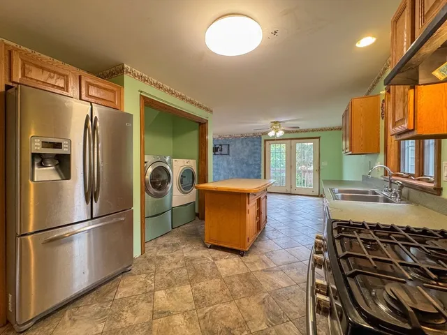 a kitchen with stainless steel appliances granite countertop a refrigerator a stove and a sink