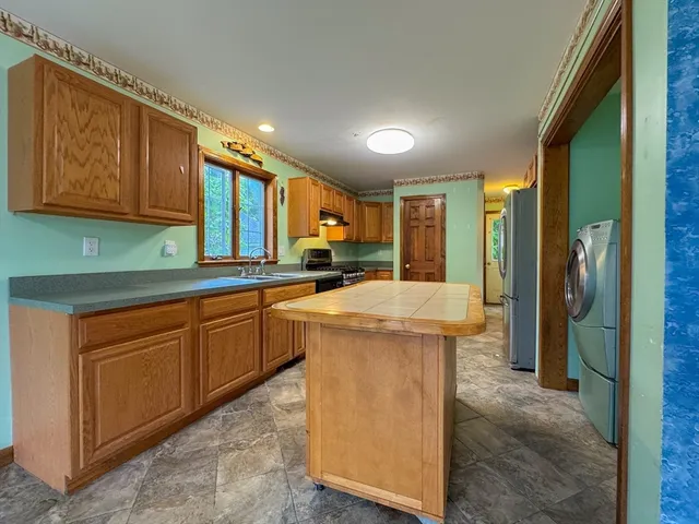 a kitchen with stainless steel appliances granite countertop a sink a stove and a refrigerator