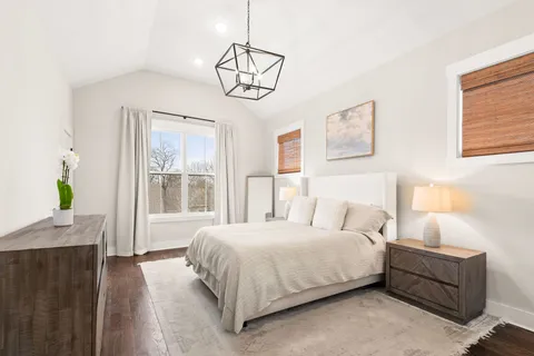 a bedroom with a bed a chandelier and a window