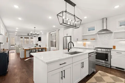a kitchen with stainless steel appliances a sink a stove a refrigerator and white cabinets