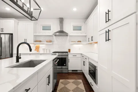 a kitchen with stainless steel appliances granite countertop a sink a stove a refrigerator and cabinets