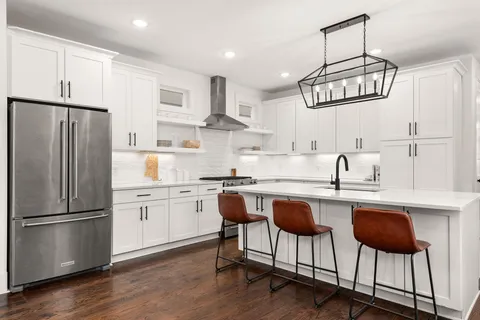 a kitchen with stainless steel appliances granite countertop a dining table chairs stove refrigerator and cabinets