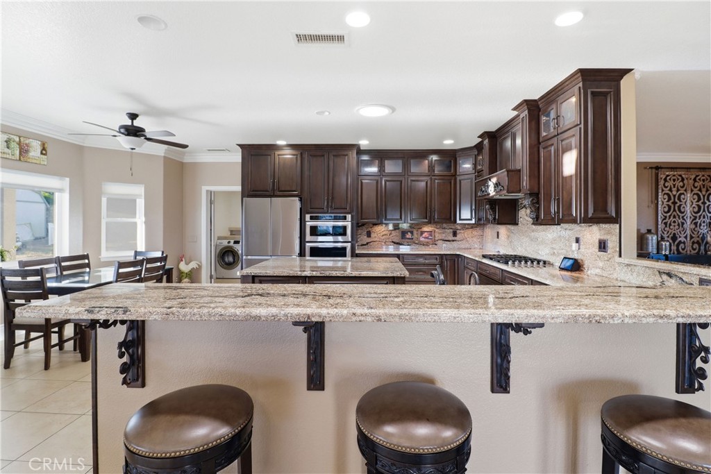 16025 Perry Heights Drive Riverside, CA 92504 - Photo 15 of 52 a kitchen with stainless steel appliances granite countertop a sink a stove and chairs