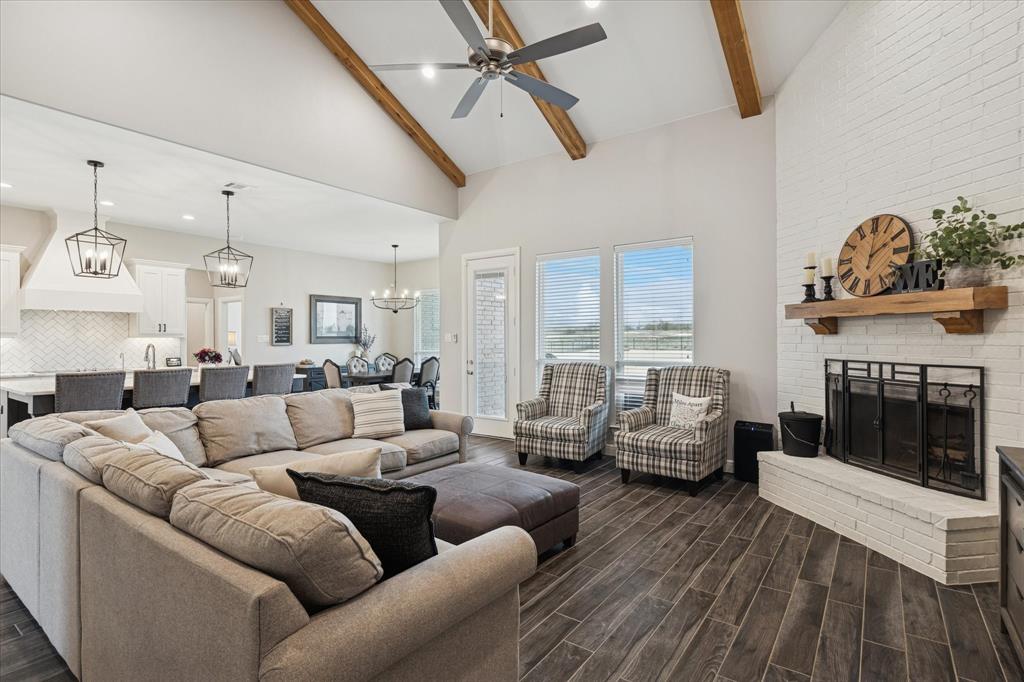 112 Friendship Way Boyd, TX 76023 - Photo 7 of 29 Vaulted living space featuring exposed wood beams, a white brick fireplace with a wood mantel, and large windows
