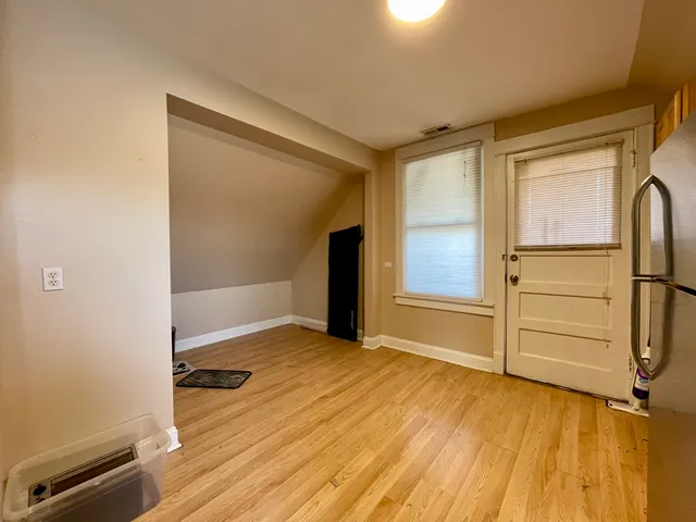 an empty room with wooden floor closet and windows