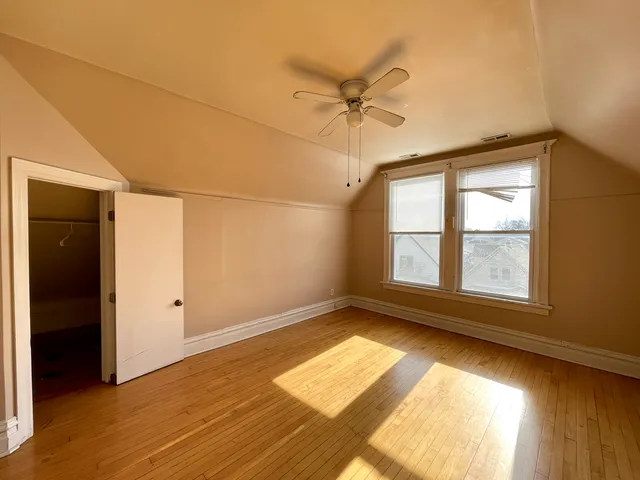an empty room with wooden floor fan and windows