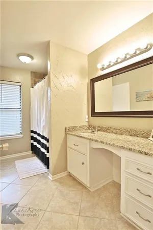 a bathroom with a granite countertop sink a mirror and a bathtub