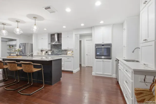a kitchen with stainless steel appliances kitchen island granite countertop a sink cabinets and wooden floor
