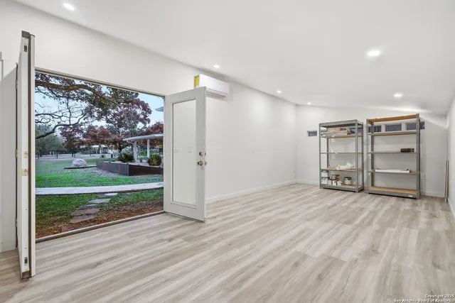a view of a big room with wooden floor a ceiling fan and windows