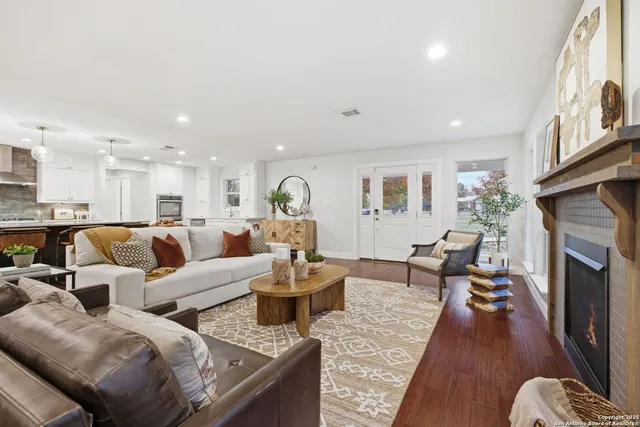 a living room with couches fireplace and a view of kitchen