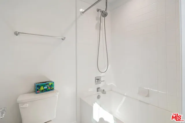 a white bath tub sitting next to a white toilet and a shower
