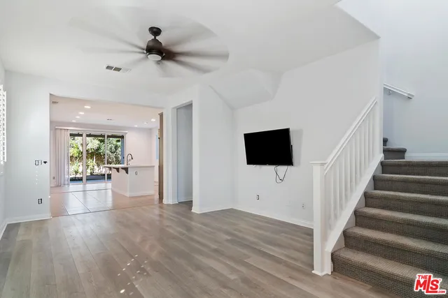 a view of a livingroom with wooden floor a ceiling fan and windows
