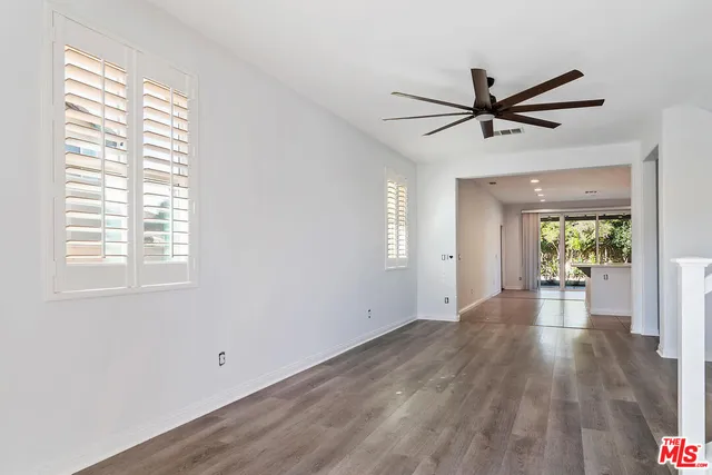 a view of empty room with wooden floor and fan