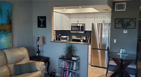 a living room with furniture a flat screen tv and a refrigerator