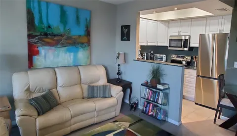 a living room with stainless steel appliances furniture a rug and a refrigerator